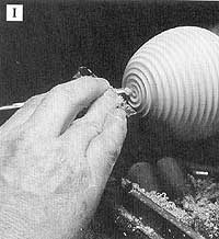 With the body friction fit into a waste block, turn coves in the box bottom with a spindle gouge.
